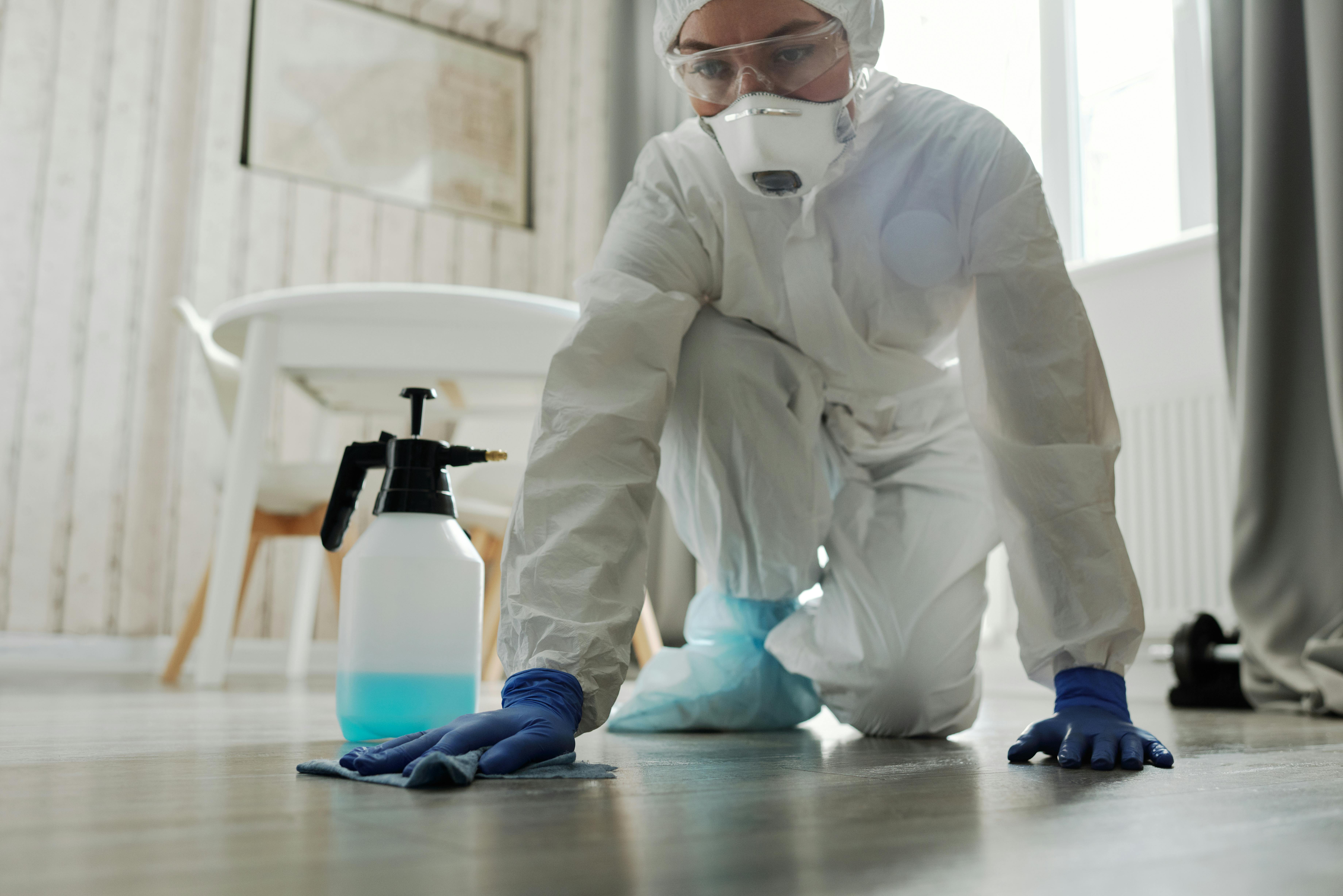 Hygiene officer in proper protective gear applying floor cleaner